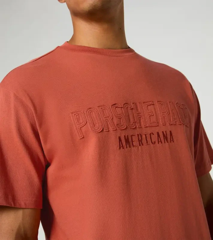 Porsche Race Americana T-Shirt Lifestyle Porsche Legacy x PUMA Tričko volnočasové s výstřihem ke krku bavlněné s reliéfním nápisem lávově oranžová