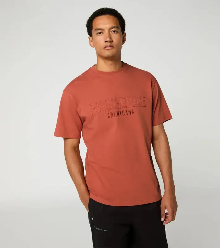 Porsche Race Americana T-Shirt Lifestyle Porsche Legacy x PUMA Tričko volnočasové s výstřihem ke krku bavlněné s reliéfním nápisem lávově oranžová